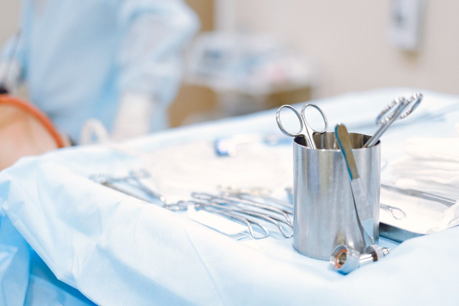 Stock photograph of metal surgical instruments on a blue-covered clinical work surface. Illustrative medical setting, not Elysian premises or product evidence.